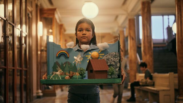 Girl carries her school project, in school with green tech theme SMALL